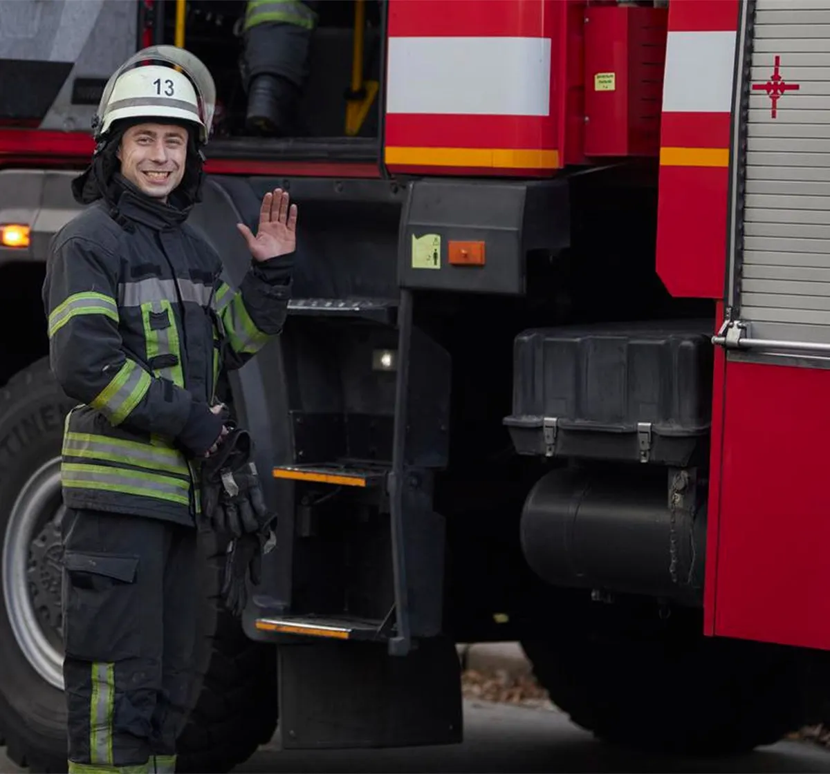 Bombero saludando junto a un camión de bomberos